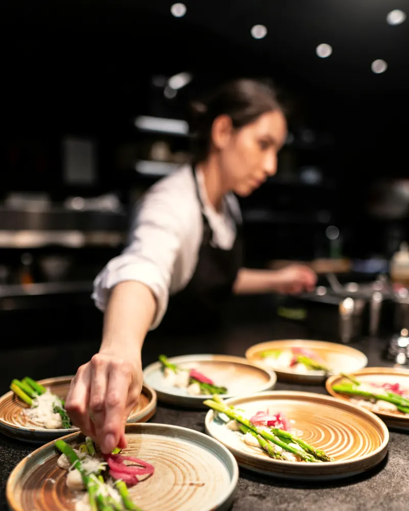 Cheffe dressant des asperges sur des assiettes en céramique