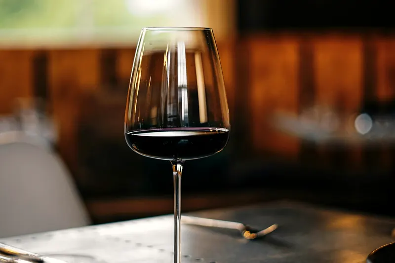 Verre de vin rouge sur une table, devant une fenêtre